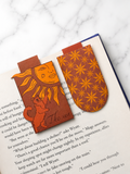 Two magnetic bookmarks with sun designs placed on open book pages