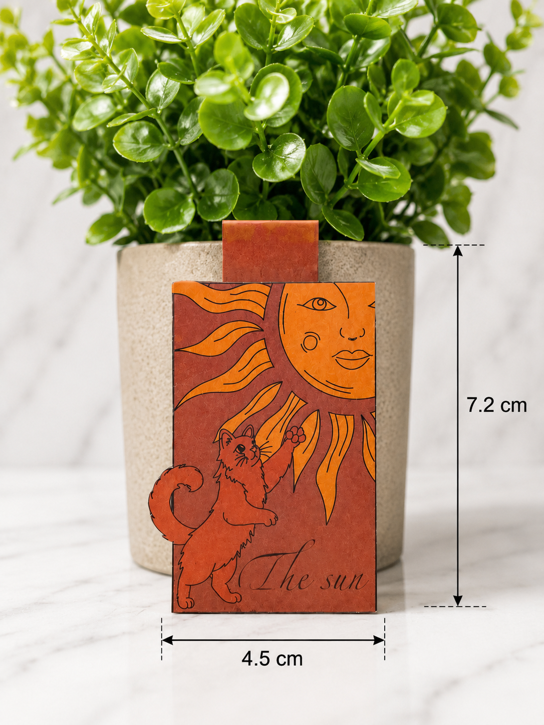 Magnetic bookmark featuring a cat reaching toward a stylised sun illustration in warm orange tones