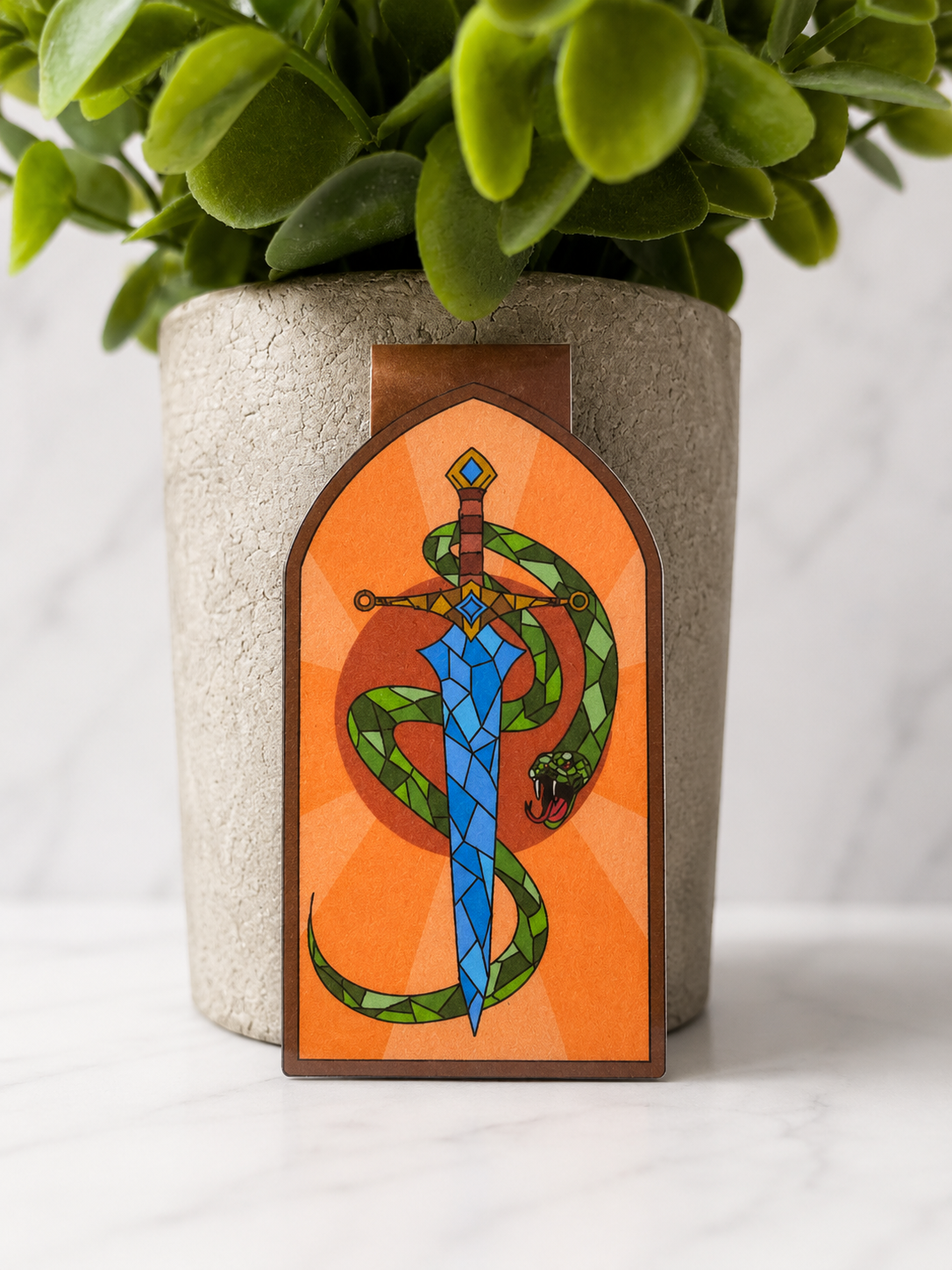 Fantasy magnetic bookmark showing a blue sword with a green snake wrapped around it on an orange background