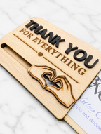 Close-up of engraved wooden gift card holder showing hand heart design and sliding slot mechanism