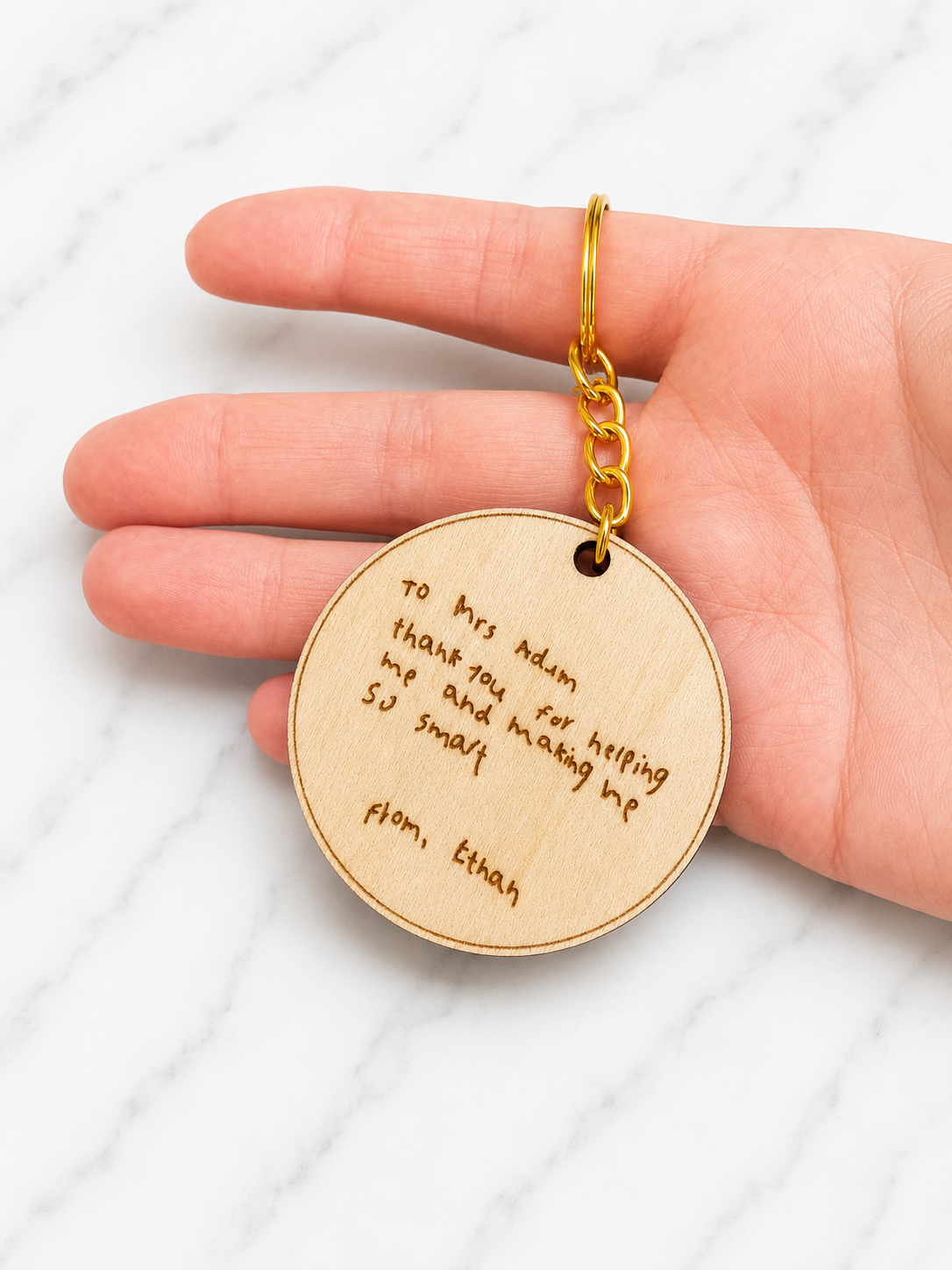 Engraved wooden keychain showing custom handwritten message held in hand to display size