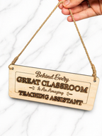 Hand holding wooden teaching assistant sign with rope hanger showing size and scale of classroom gift plaque