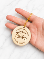 Engraved wooden teacher keychain with thank you message and decorative design held in hand