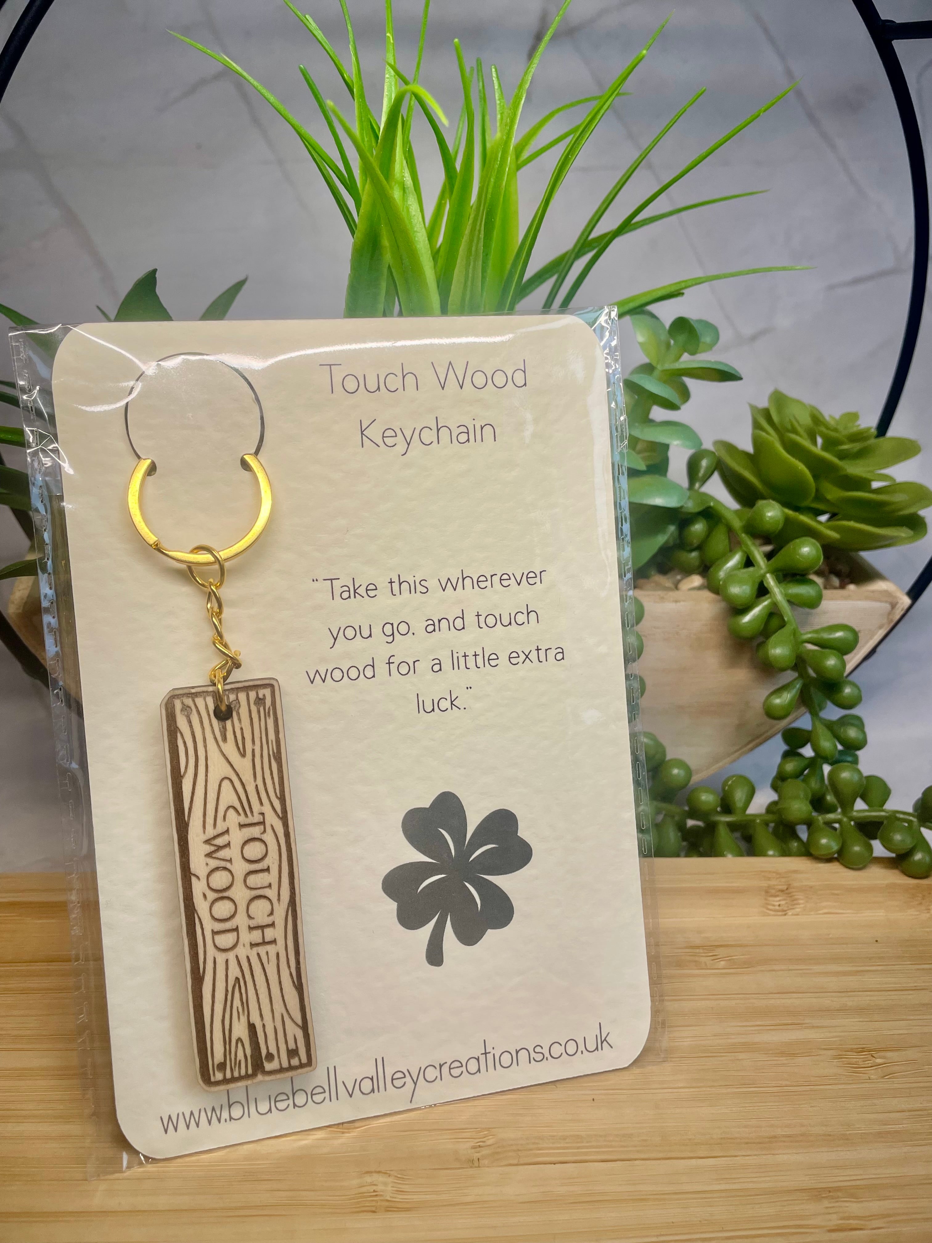 Touch Wood keychain on a card with plants in the background