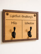 Wooden board with two hooks and engraved names on a white background