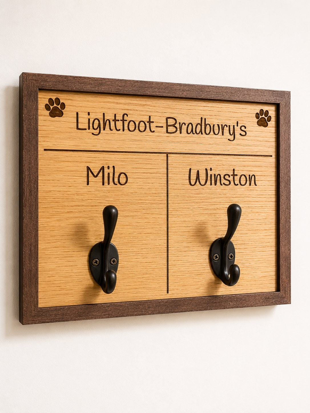 Wooden board with two hooks and engraved names on a white background