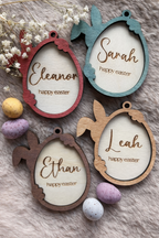 Four decorative Easter egg-shaped tags for baskets with names and 'happy easter' text, surrounded by Easter eggs and flowers.