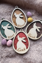 Wooden Easter tag with a bunny and butterfly inside an egg wit ha floral stained background. There are 4 tags with different colours and names.