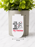 Magnetic bookmark with funny voodoo doll design and the quote “If you can’t kill them with kindness try voodoo”, shown with measurements 7 cm by 3.5 cm on a marble background with plant