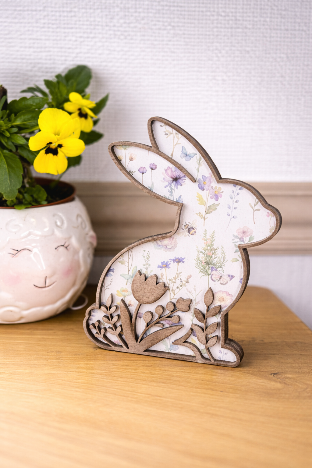 Decorative rabbit figurine with floral patterns on a white background and a cut out of flowers following the bottom silhouette of the rabbit. The silhouette is stained a dark brown for a rustic look.