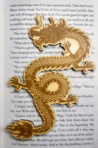 Wooden dragon bookmark on top of a page of a book 