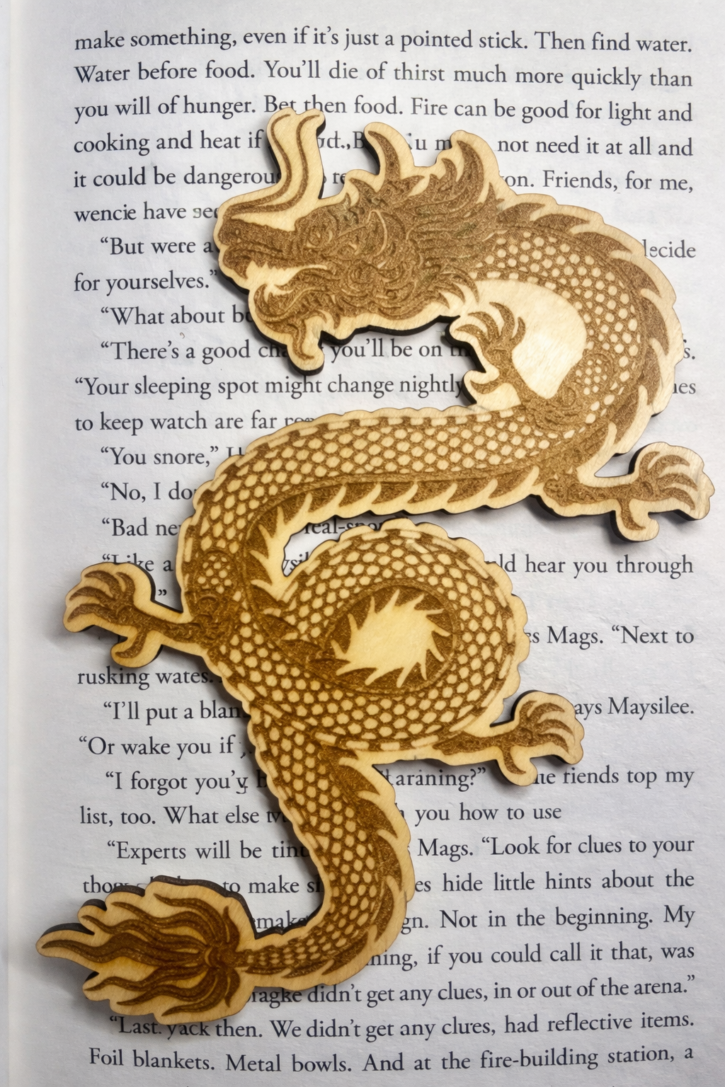 Wooden dragon bookmark on top of a page of a book 