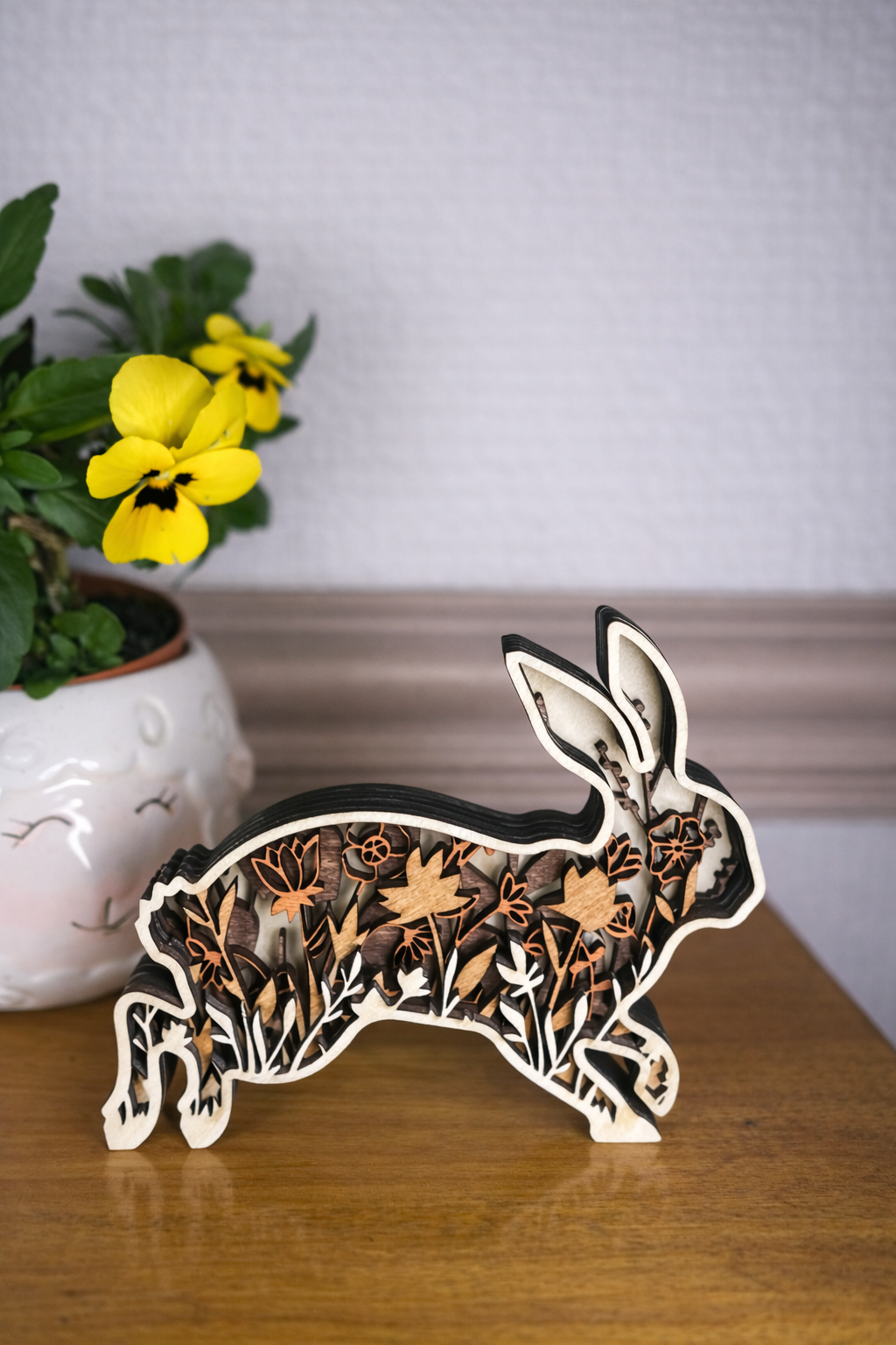 Wooden rabbit decoration with shades of brown florals layered within the silhouette.  