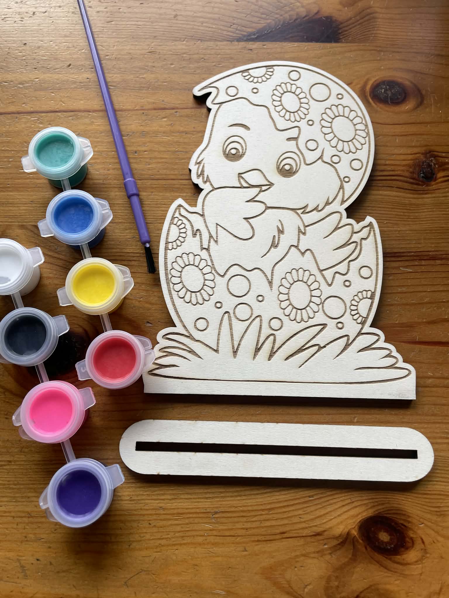 close up of a wooden hatched chick next to a wooden stand 