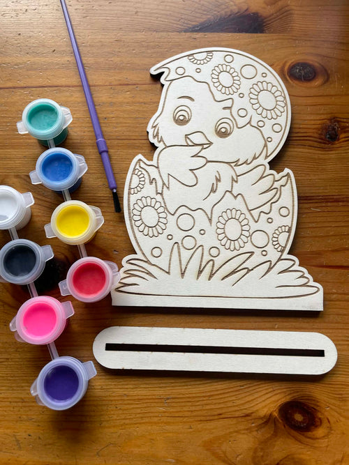 close up of a wooden hatched chick next to a wooden stand 