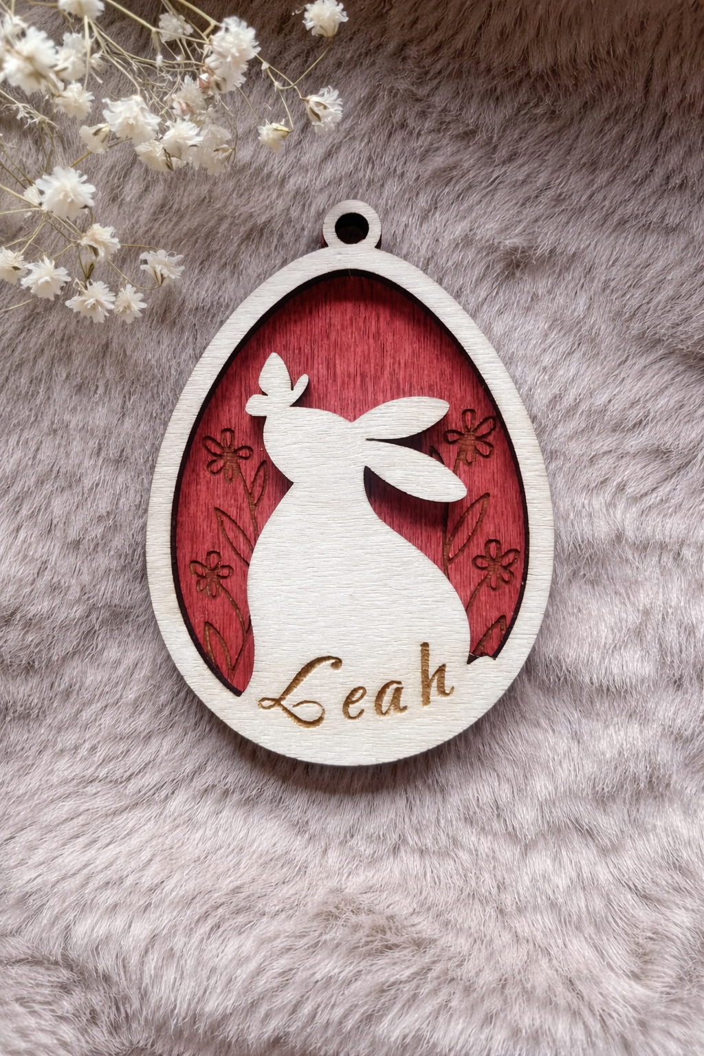 Wooden tag with a bunny and butterfly inside an egg with floral background stained red. On the bottom is space for a personalised name.